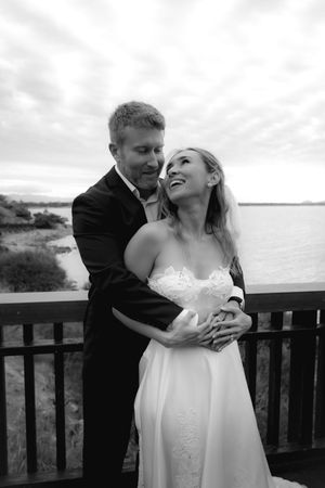 A romantic moment captured between newlyweds on an oceanside deck.