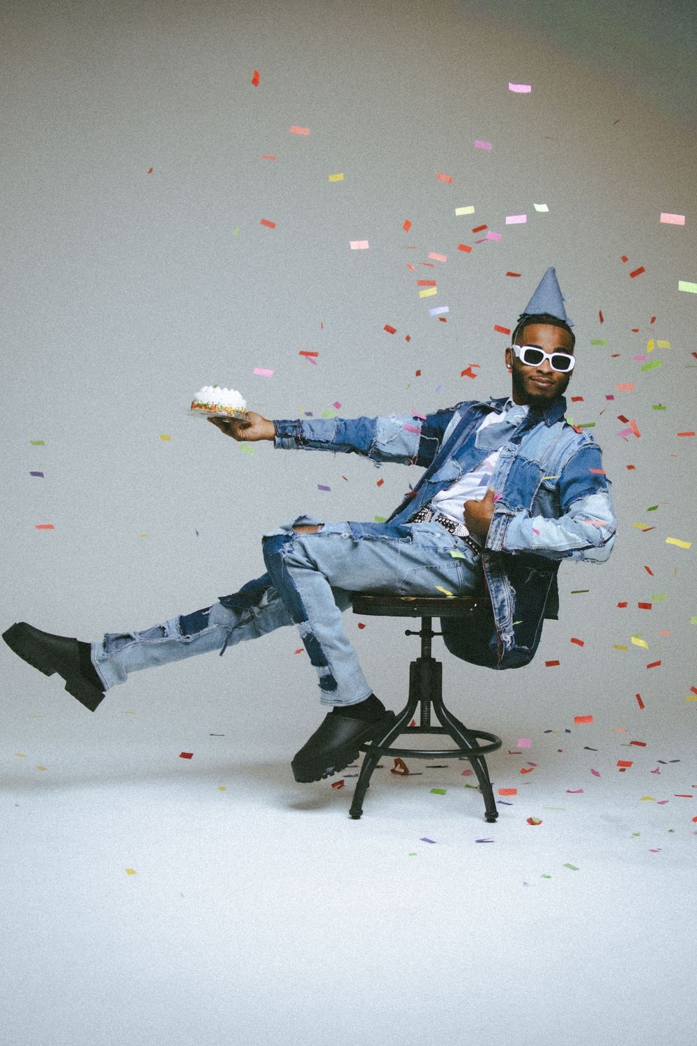 Person in denim and party hat performs dynamic poses amid falling confetti.