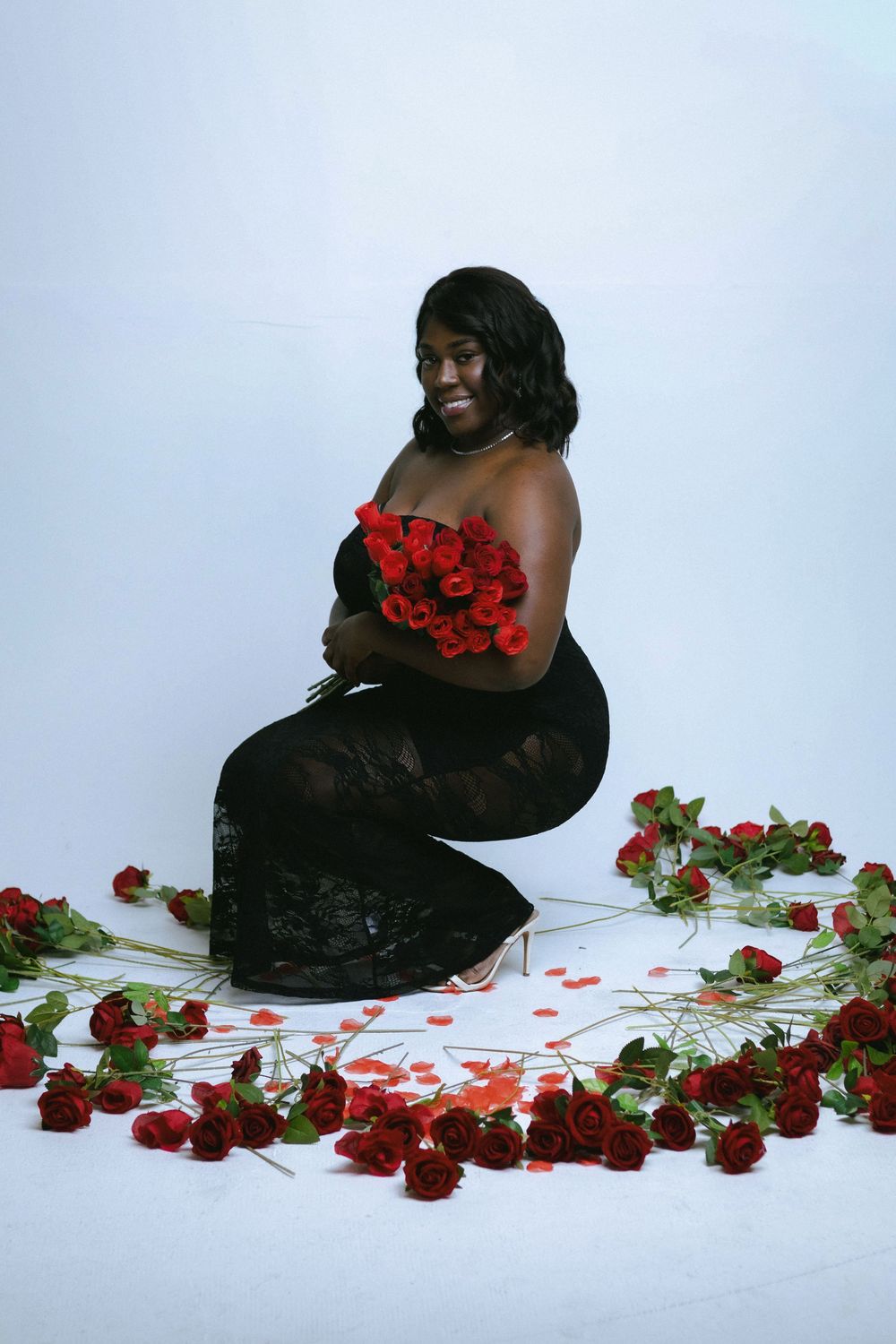 Artistic portrait with red roses scattered on white background creating romantic atmosphere.