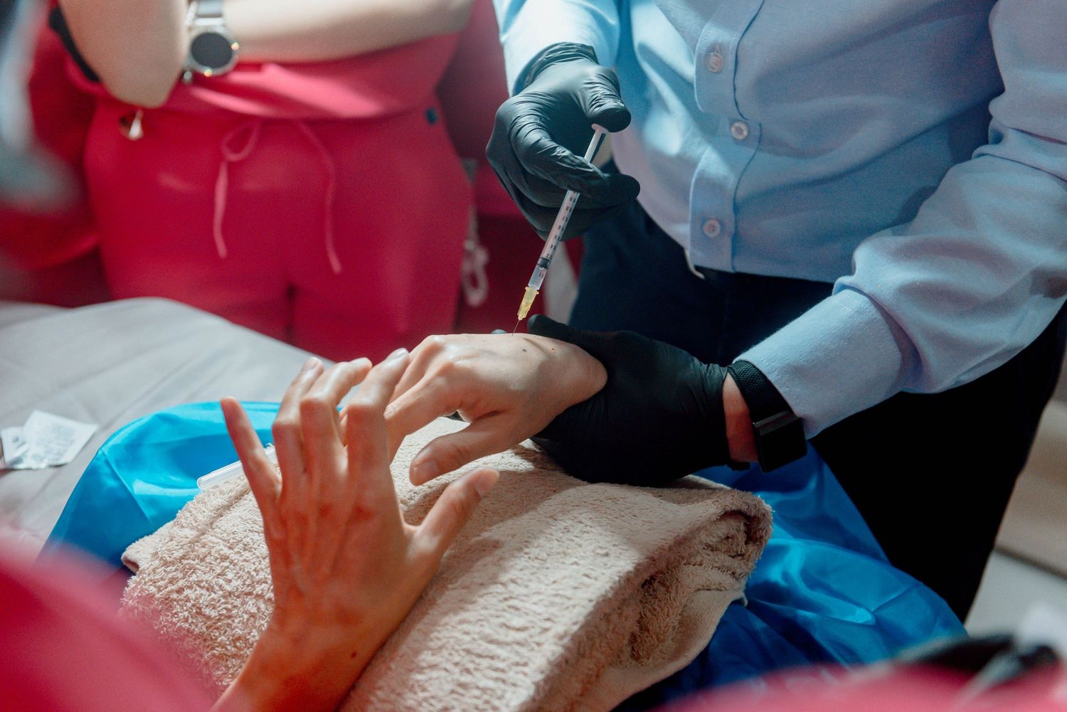Medical professional in blue scrubs performs dental examination while patient reclines in dental chair.