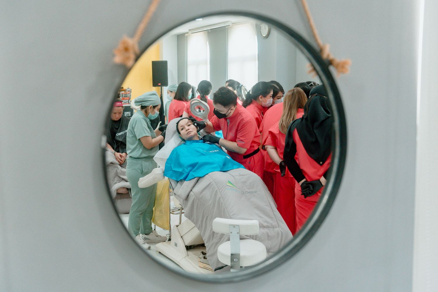 A row of circular wall mirrors reflects a busy hallway scene with people in colorful clothing.