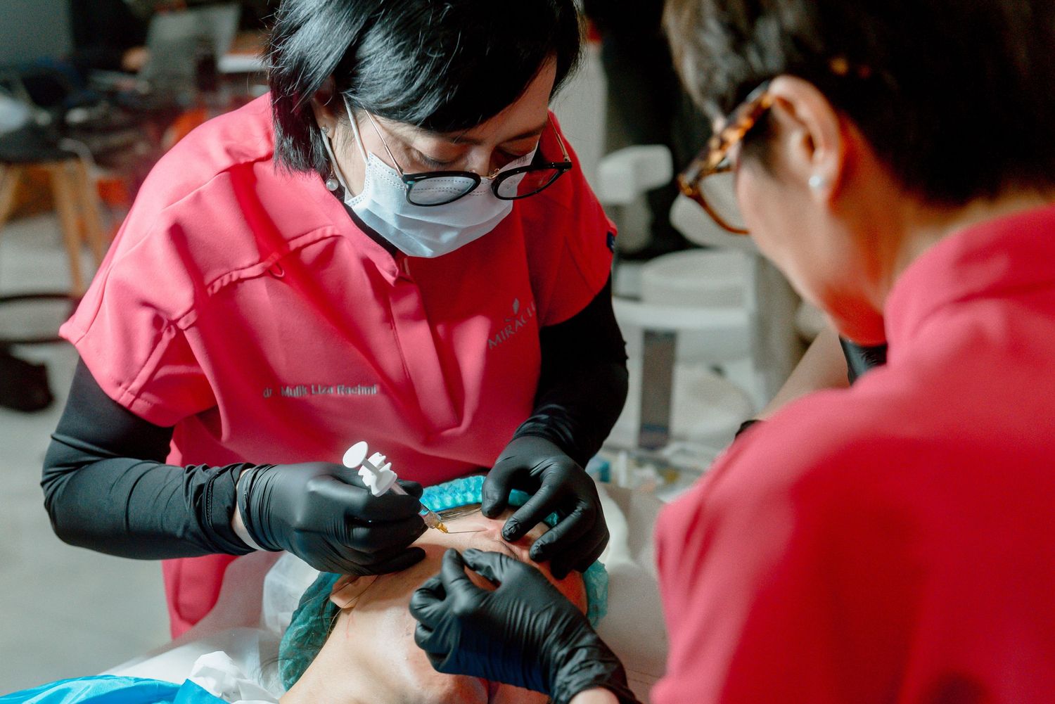 Medical professional wearing protective gloves performs a dental procedure on a patient in a clinical setting.