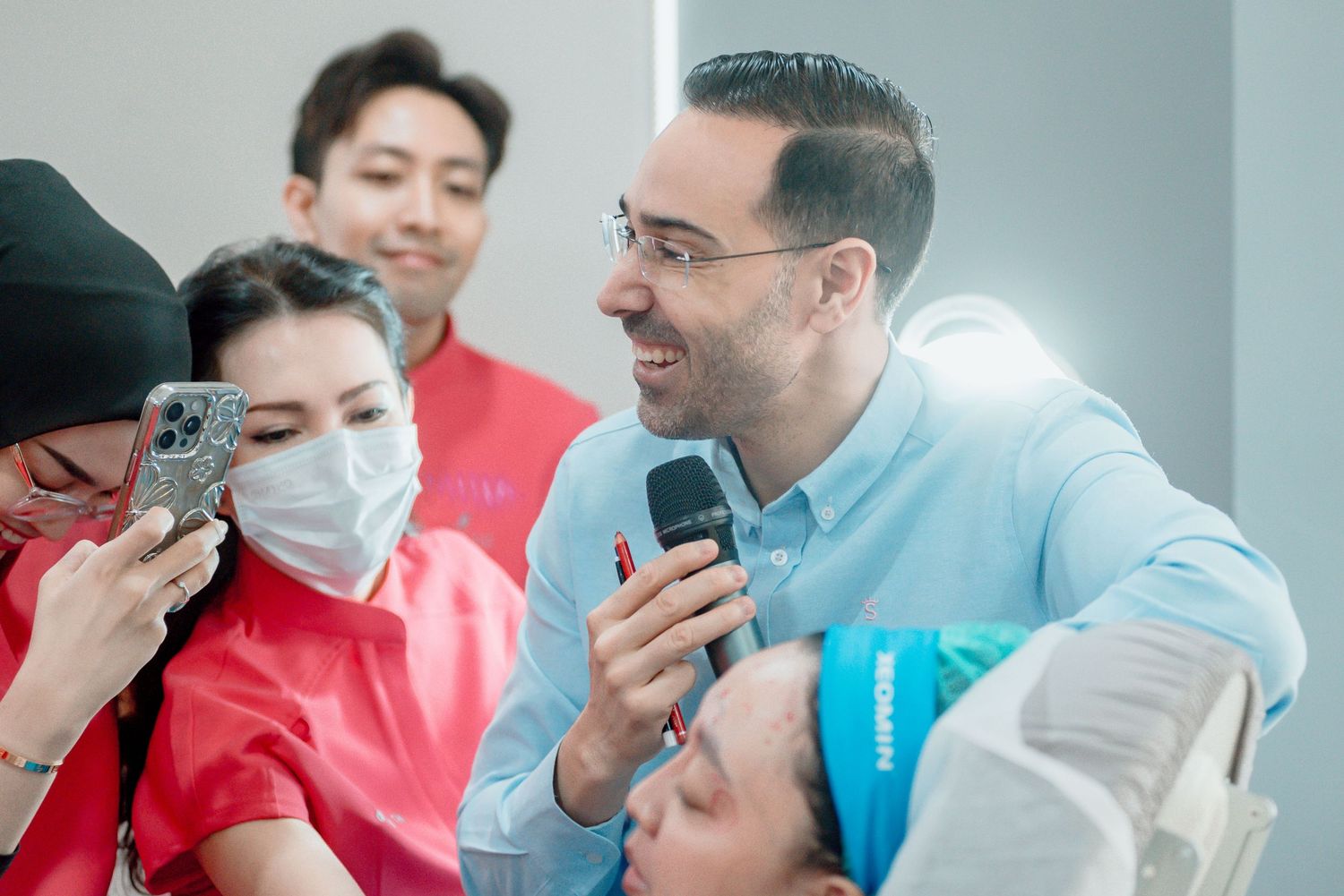 A group of people gather around a microphone during an interactive presentation in a bright indoor setting.