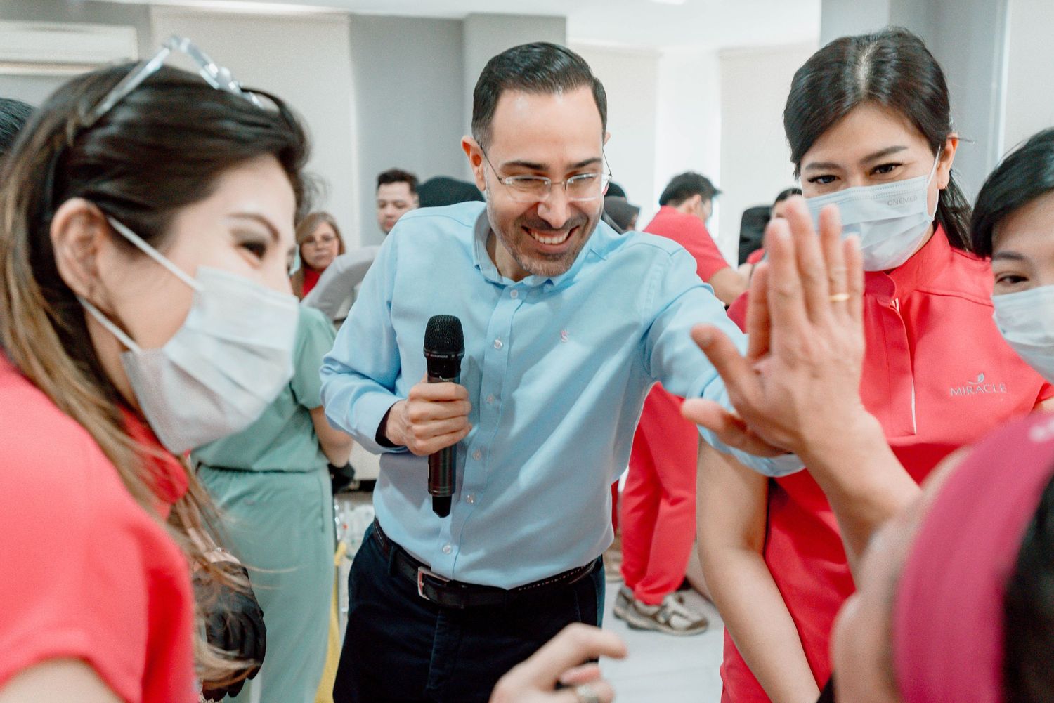 A group of people in medical scrubs laughing and smiling together in a healthcare setting.