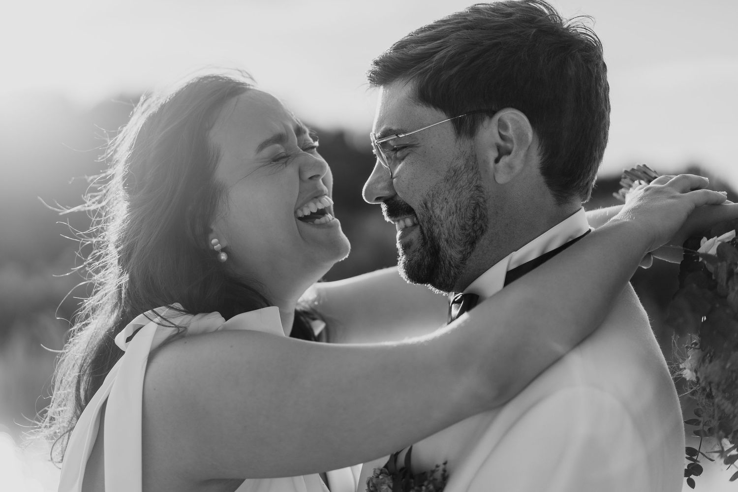 A joyful black and white portrait of a couple laughing and embracing in an intimate moment.