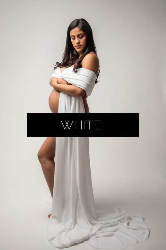 Elegant maternity portrait with figure wrapped in white fabric against minimalist gray background.