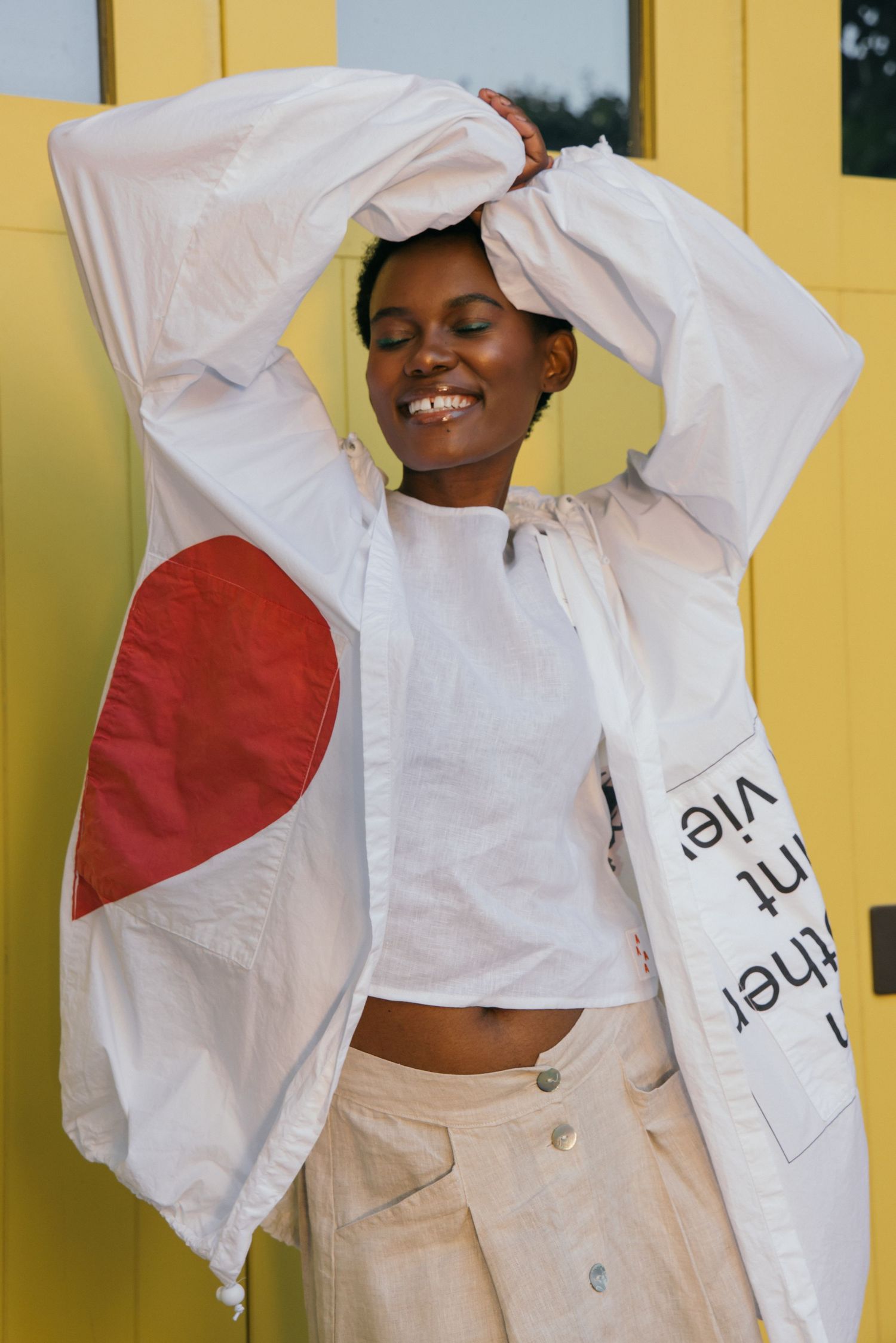 Casual style portraits in white shirt and beige pants against yellow wall.