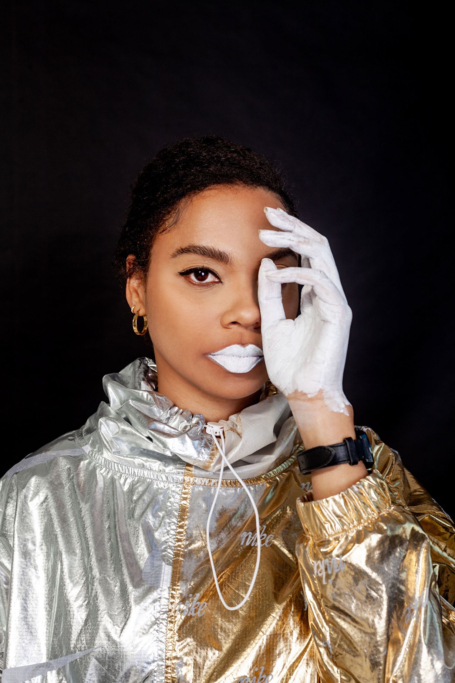Artistic portrait series in metallic silver jacket with white gloves against dark background.