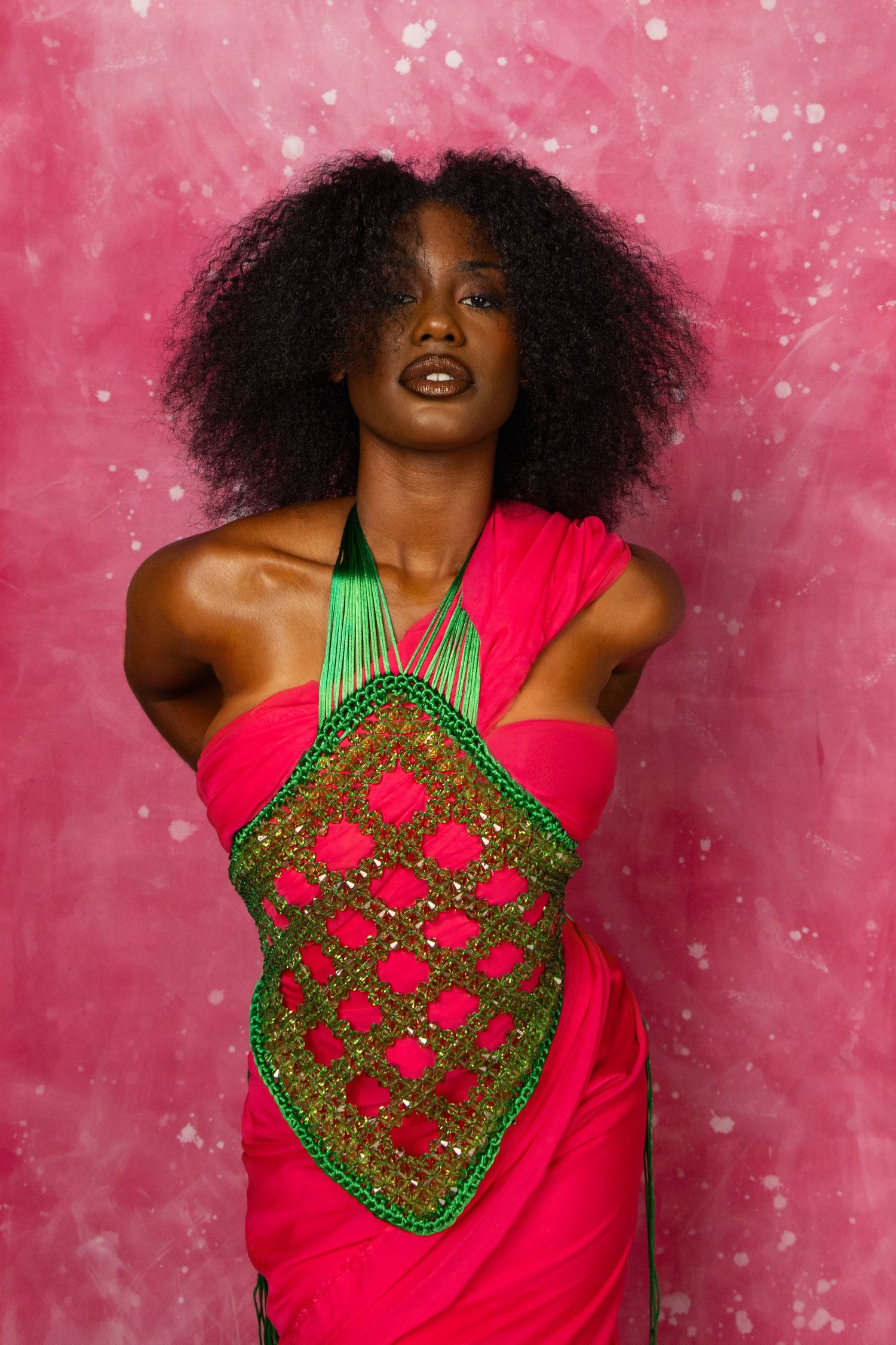 Fashion series featuring red and green geometric pattern top against pink sparkly background.