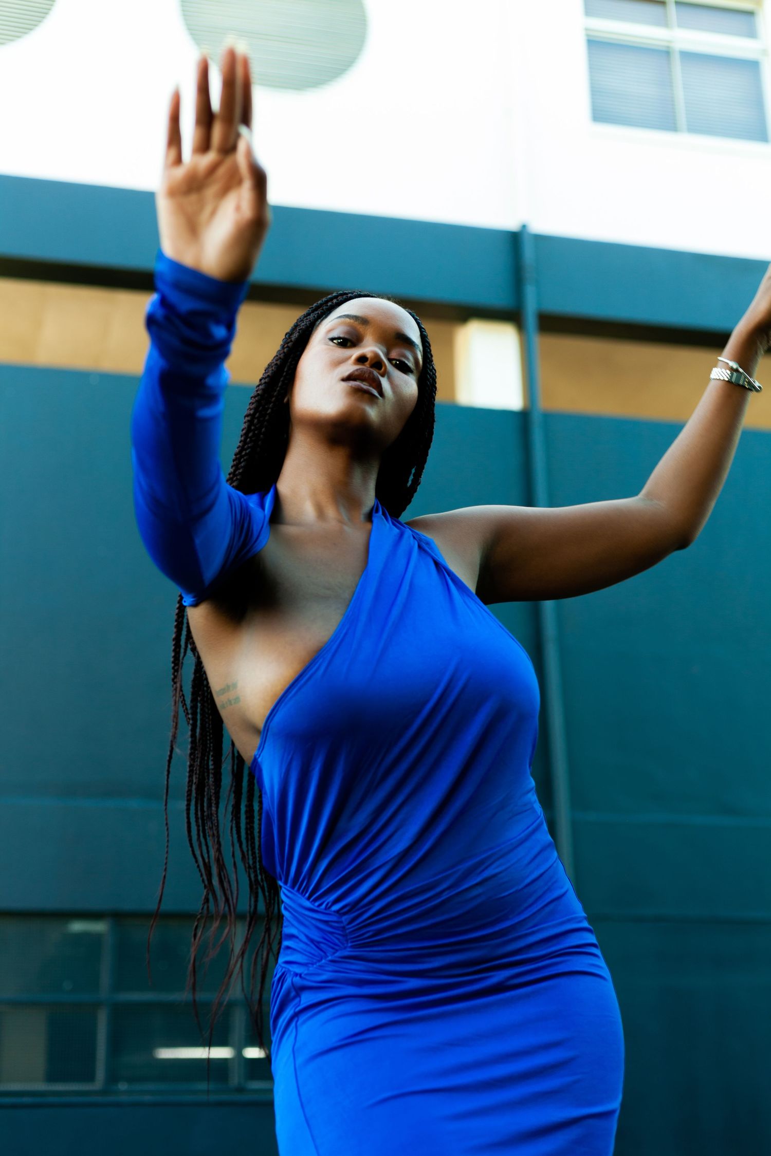 Graceful dance movements in a royal blue dress against an architectural backdrop.