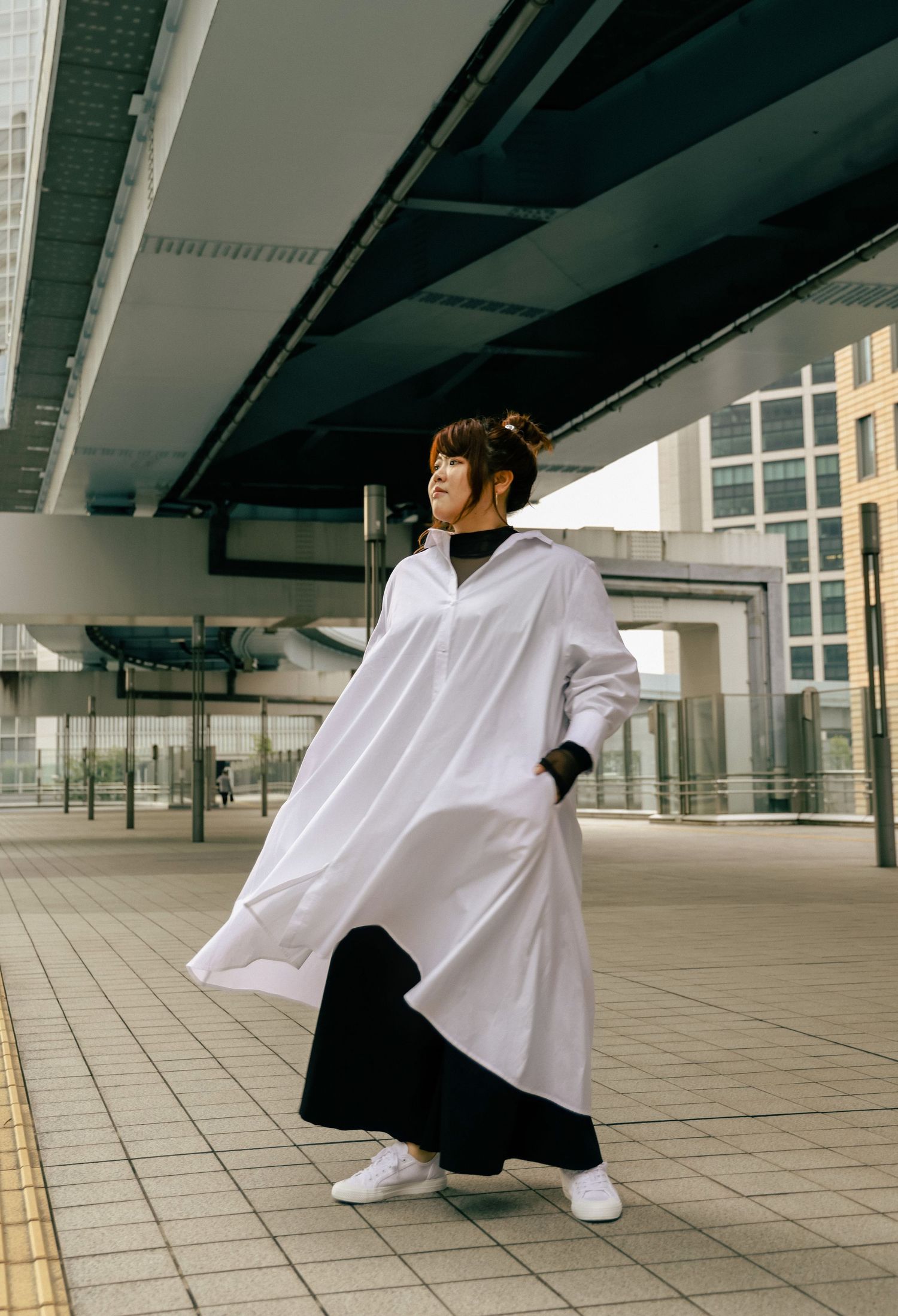 Person in flowing white outfit performs dynamic poses against modern architectural backdrop.