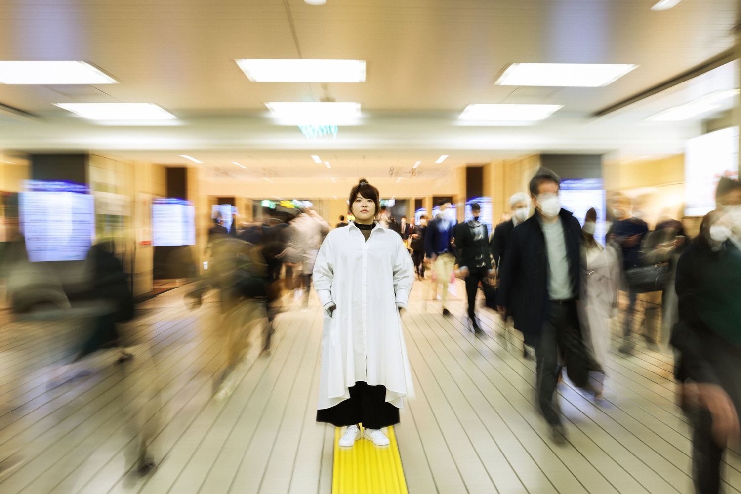 Blurred motion shot of people walking through bright indoor corridor.
