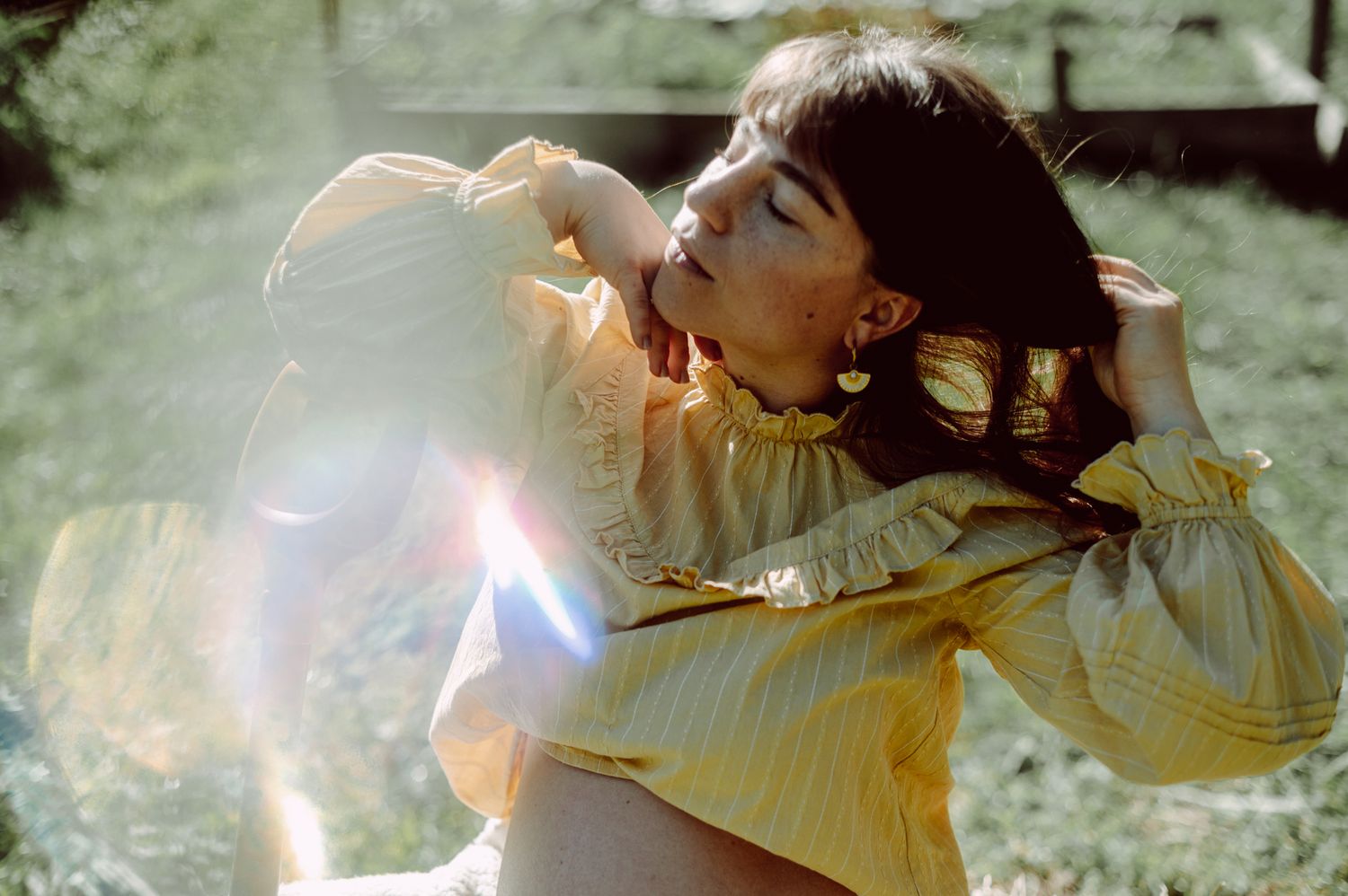 A person in white clothing lies down while sunlight creates a dreamy, ethereal glow through their hair.
