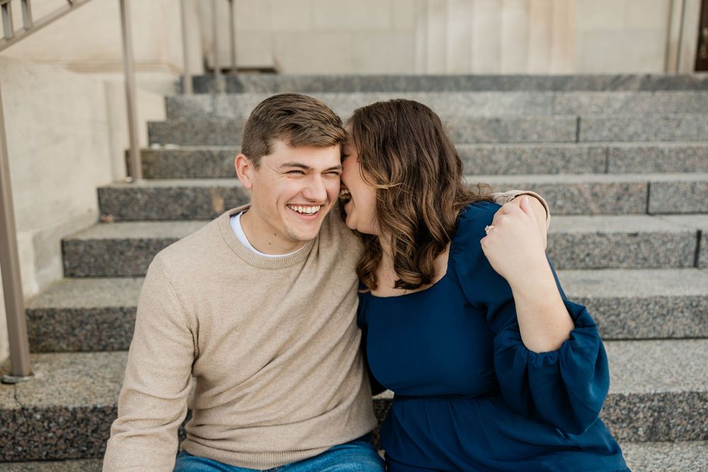 Couple shares intimate moment while sitting on concrete steps.
