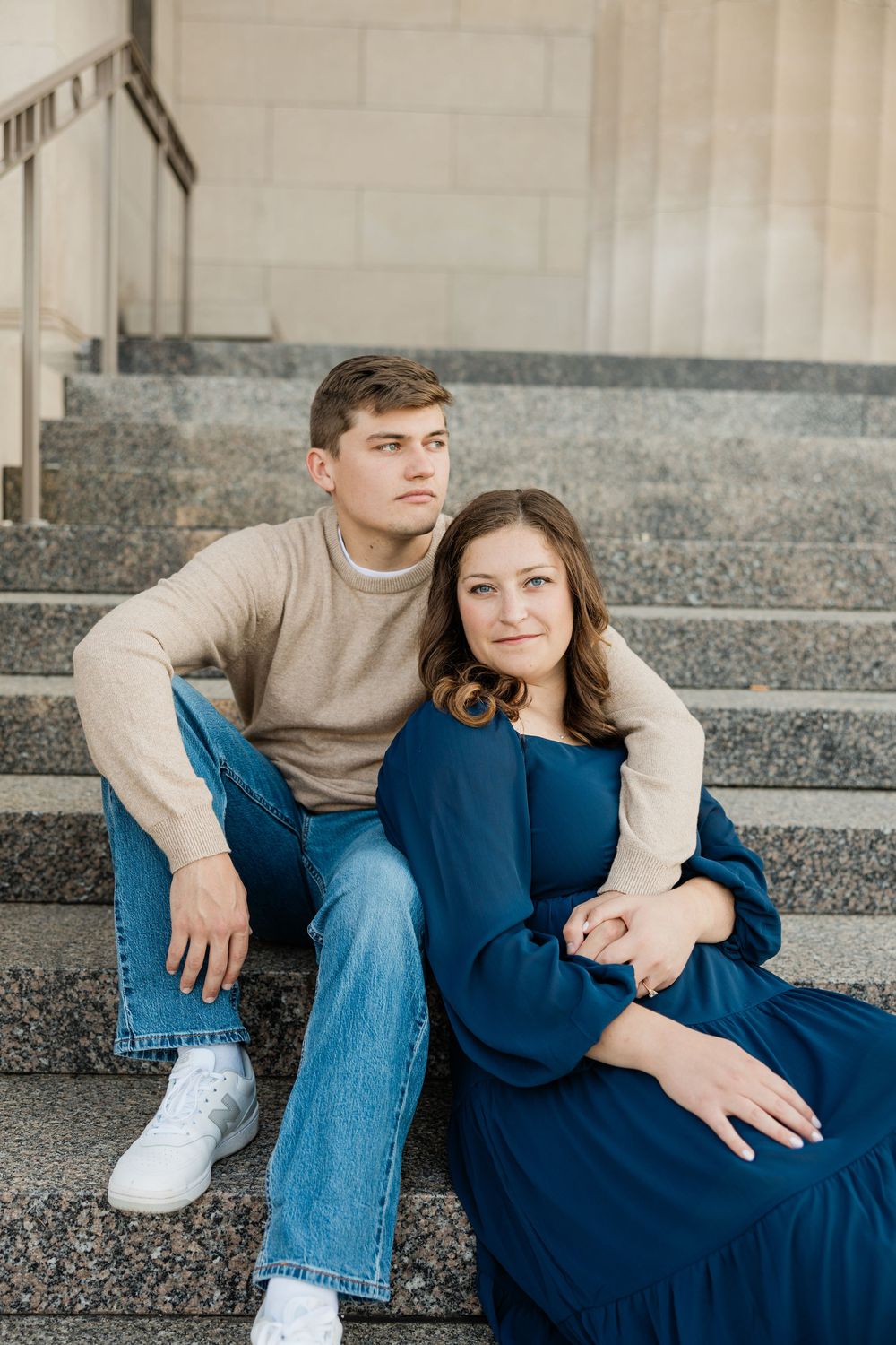 A couple relaxes on stone steps in a contemporary architectural setting.