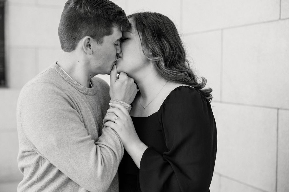Romantic couple sharing intimate moments in black and white photo series against white wall.