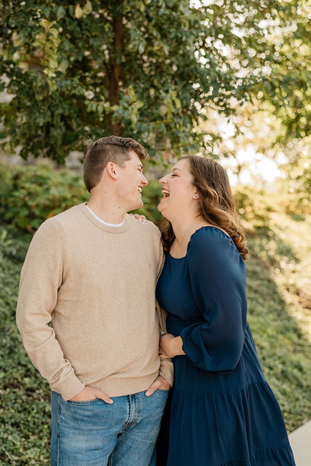 A couple in navy and beige outfits share a joyful moment outdoors.