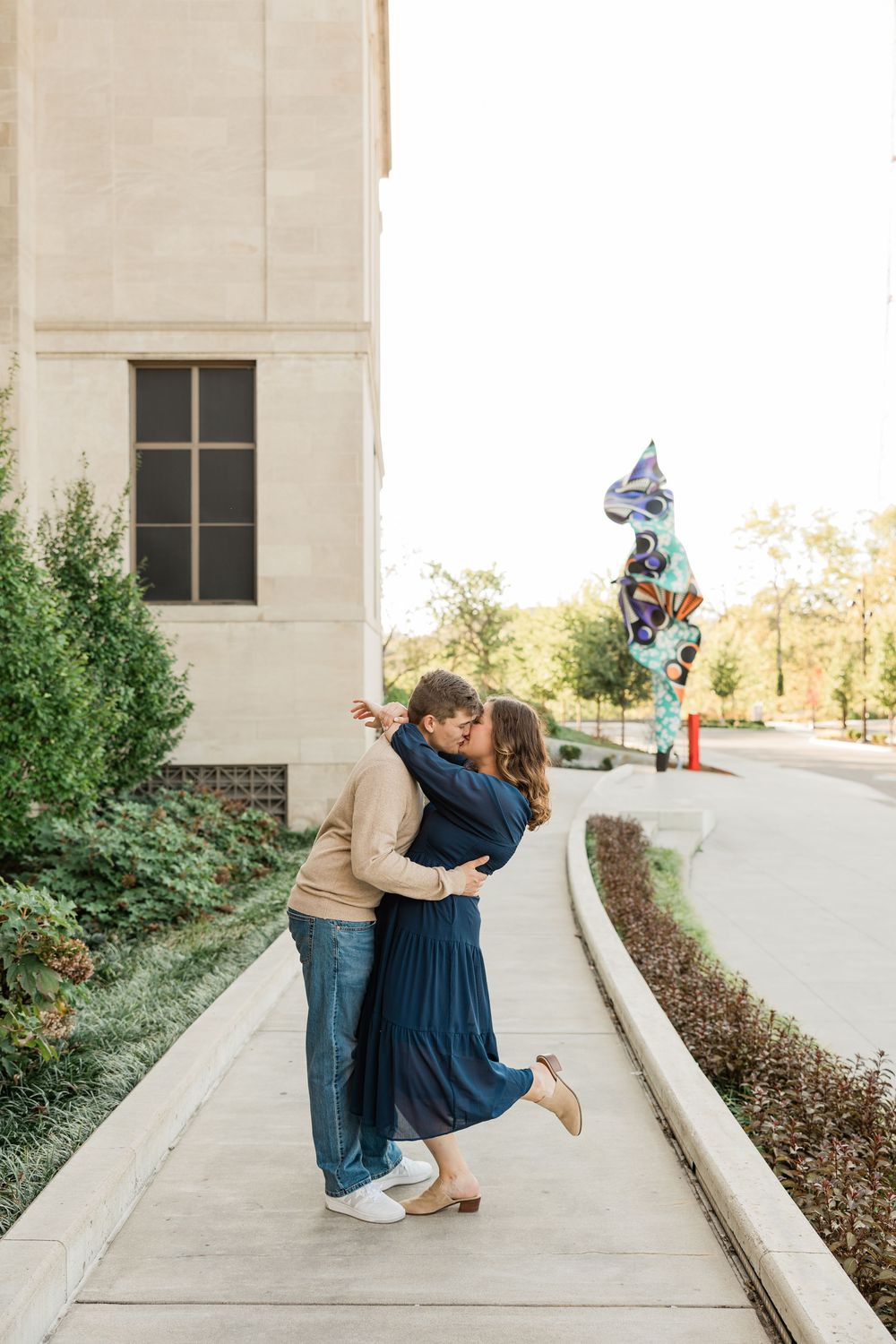 A playful couple poses on a concrete walkway during an engagement photoshoot.