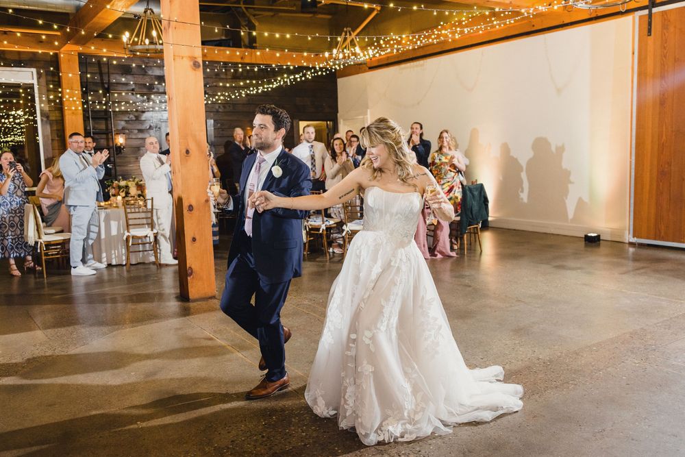 Wedding reception venue decorated with romantic string lights and rustic wooden beams.
