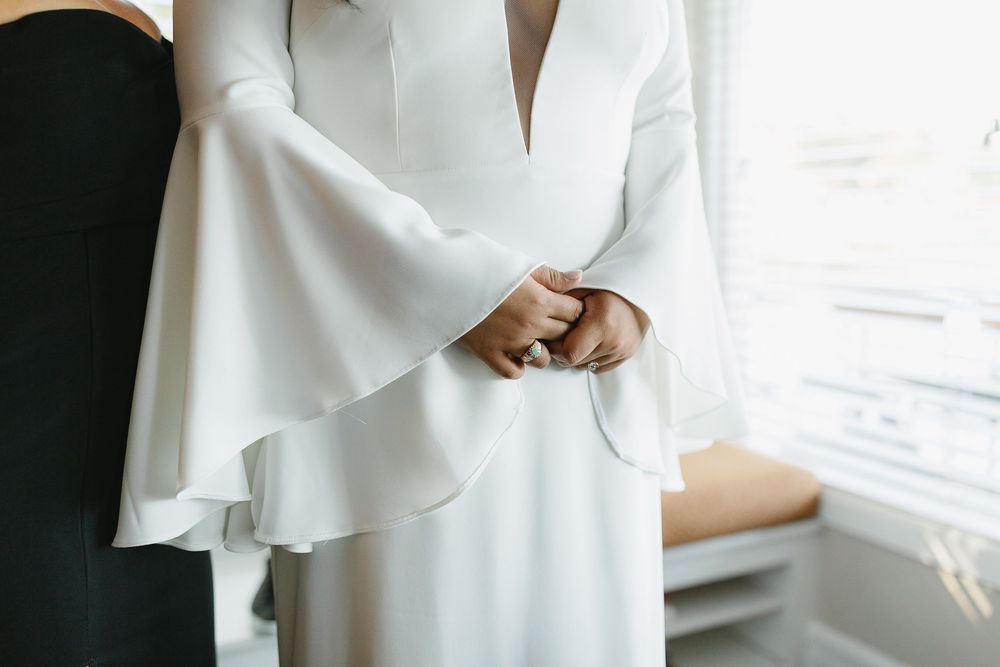 Close up of elegant white wedding dress with dramatic bell sleeves and v-neckline in natural window light.