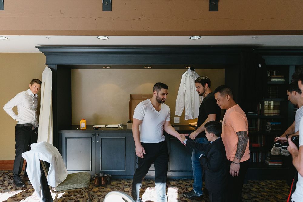 Groomsmen getting ready in a hotel room before a wedding celebration.