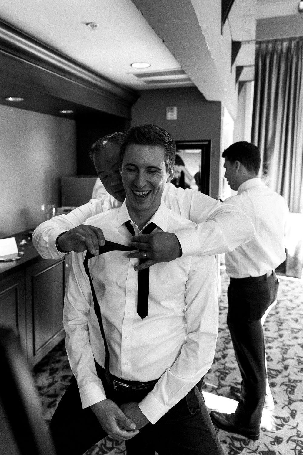 Black and white photos of wedding party preparations in a hotel room.