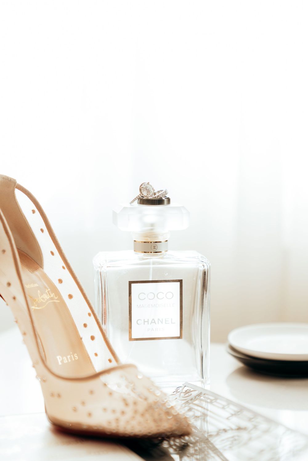 Bridal flat lay featuring Christian Louboutin heels, diamond ring, and Chanel Coco perfume.