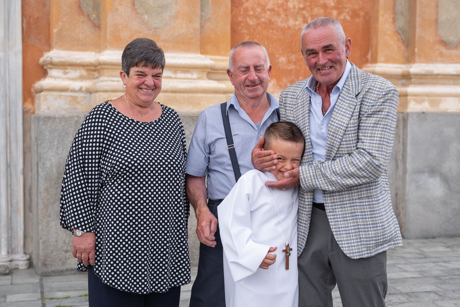 A small family group poses together outside a historic church building during a celebration.
