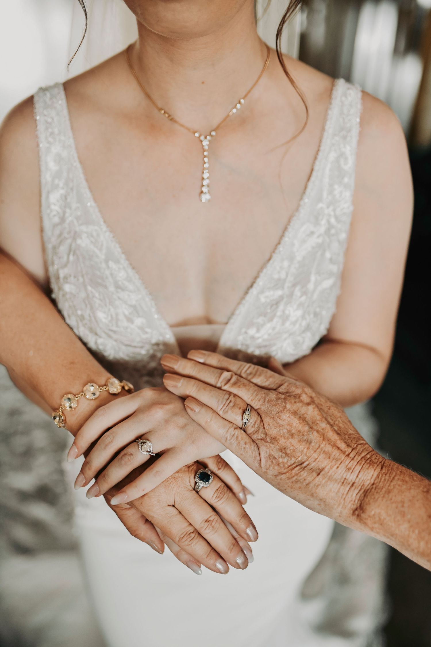 Bride, mother, and grandmother holding hands during a beautiful generational wedding photo on the wedding day.