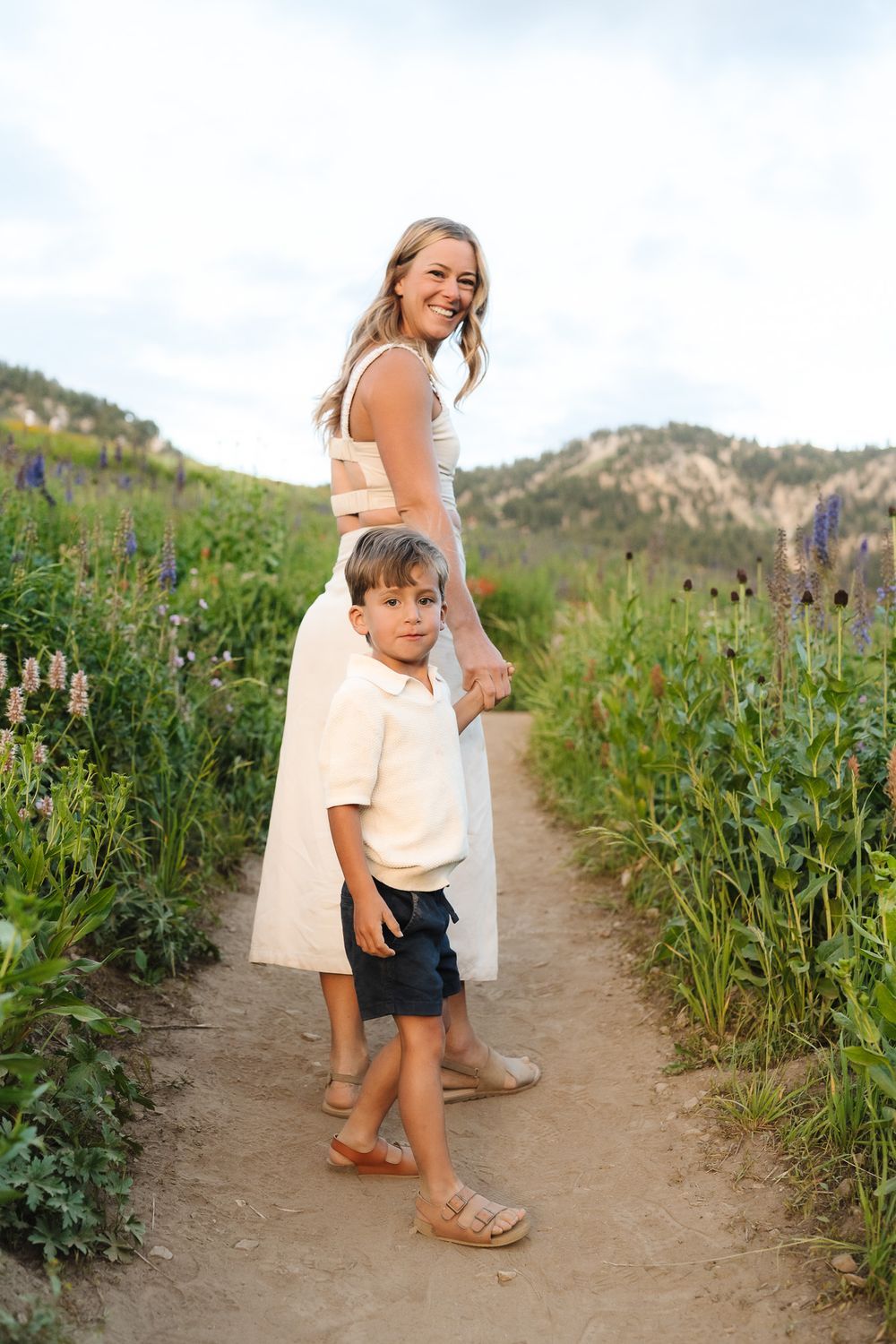 A series of photos showing people walking through a scenic mountain path lined with tall wildflowers and poppies.