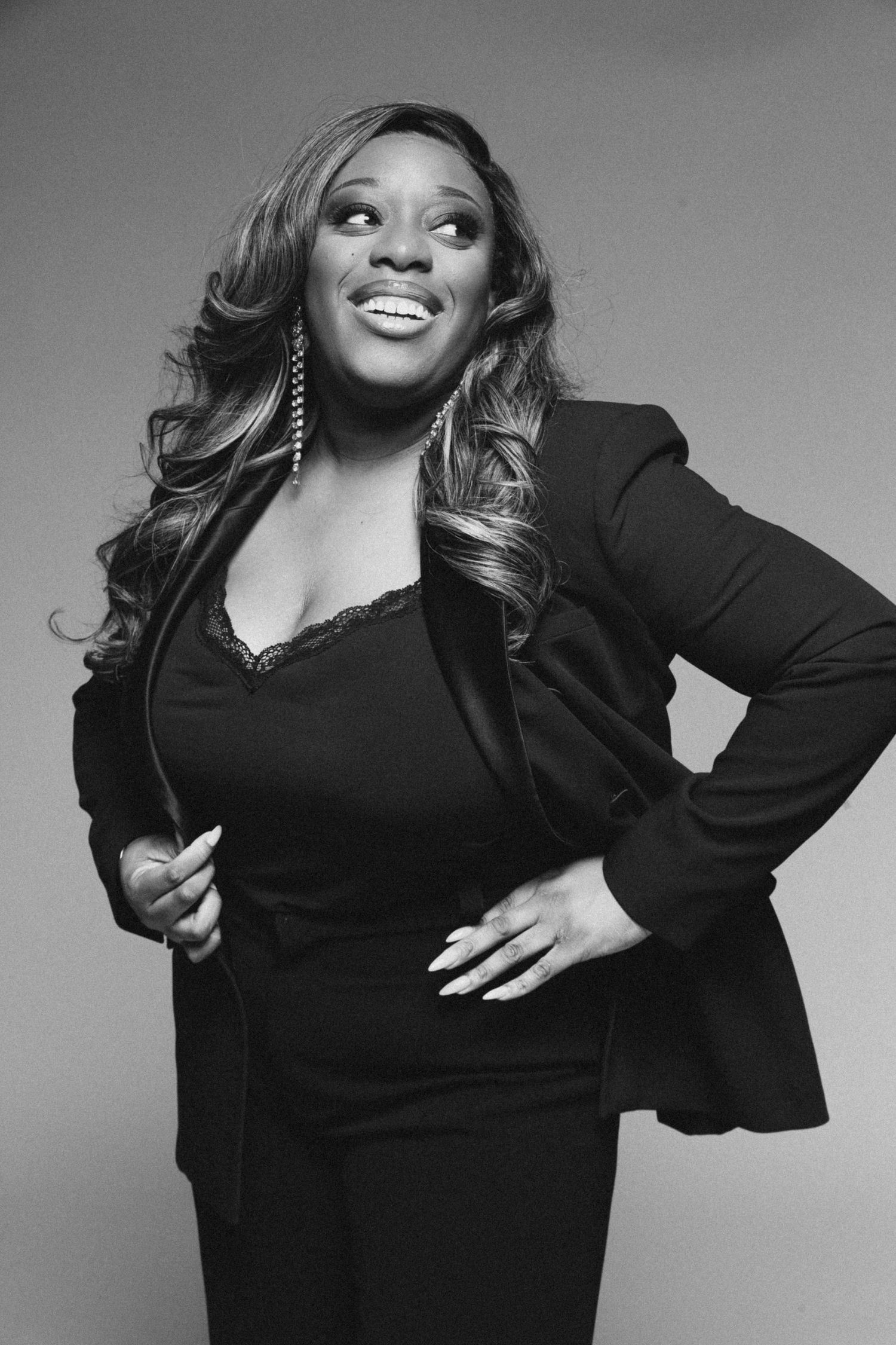 Professional studio portrait in black and white showing a woman in a black blazer and flowing hair.