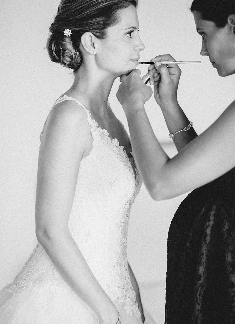 Bride having lipstick applied during wedding morning preparations.
