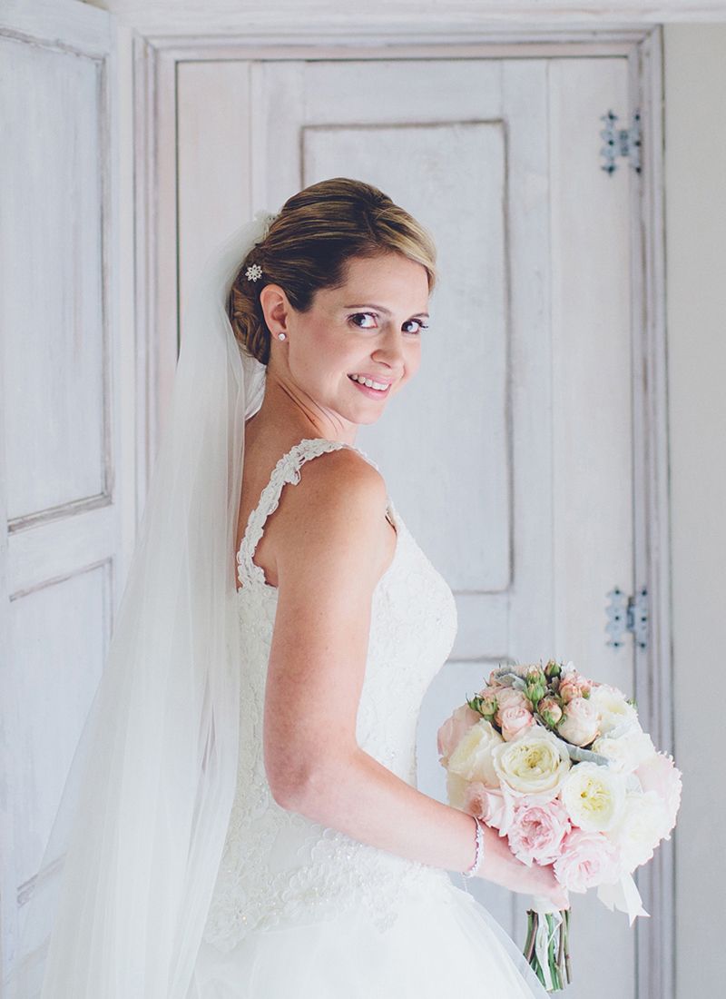 Bride smiling over her shoulder in her lace wedding dress.