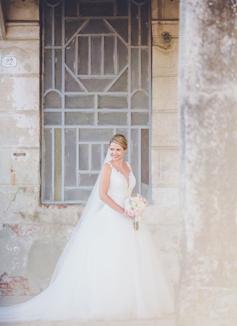 Bride standing in a doorway holding her bouquet before the ceremony.