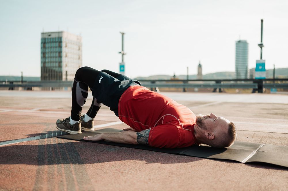A person in a red shirt lies on the ground while performing a dynamic stretching exercise sequence.