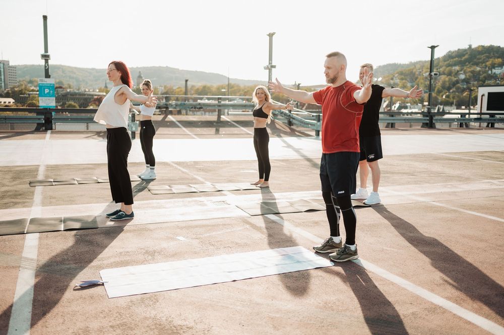 A group practices yoga poses on an outdoor terrace overlooking a coastal landscape during a morning fitness session.