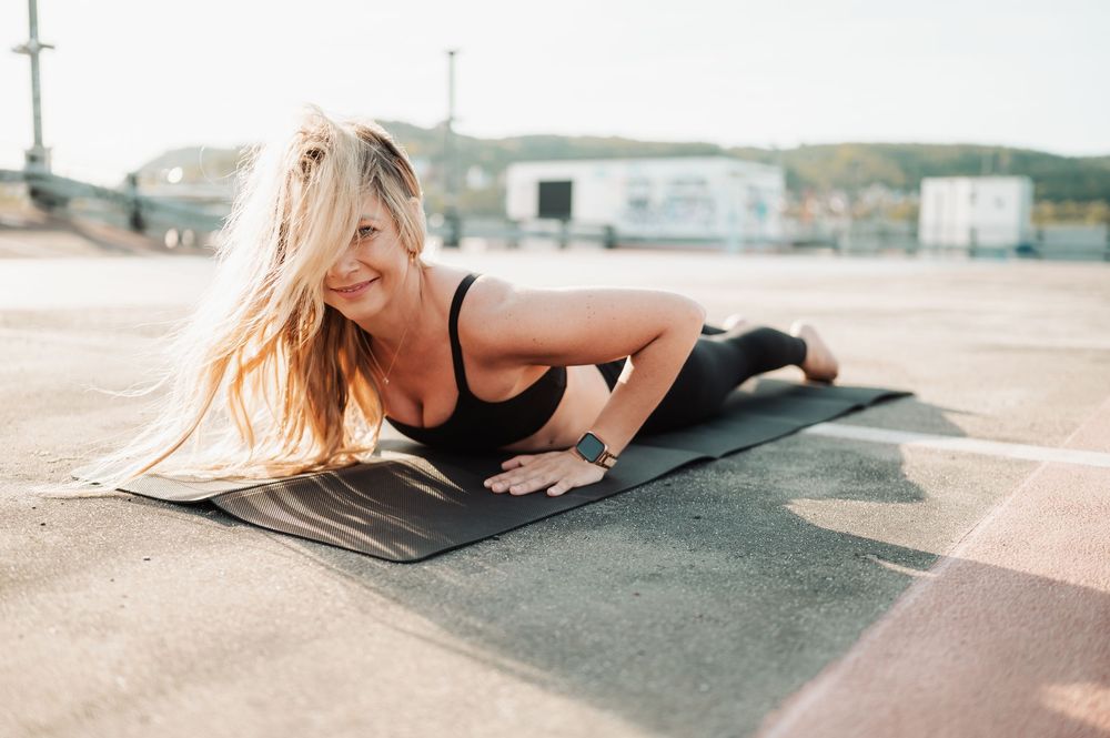 A person in athletic wear performs a series of yoga poses on a gray yoga mat outdoors at sunset.