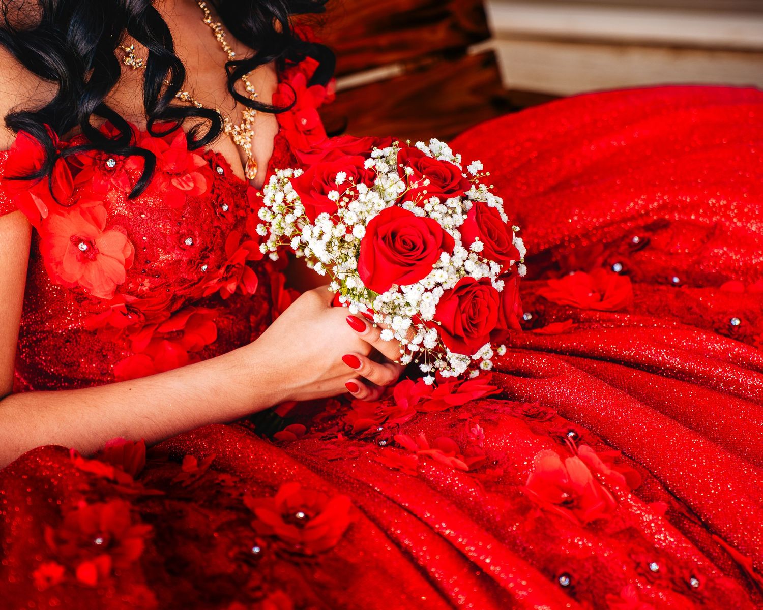 A vibrant red wedding dress with delicate floral details and baby's breath accents creates a stunning bridal look.