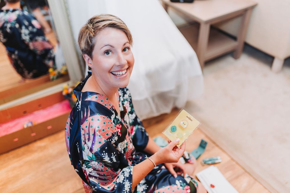Wedding preparation scene showing someone in a floral robe sitting on the floor with a book or card.