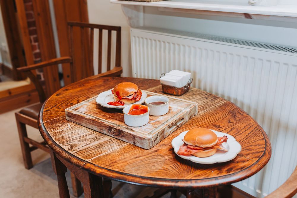 Round wooden dining table with plates and tableware arranged in a cozy cafe setting.