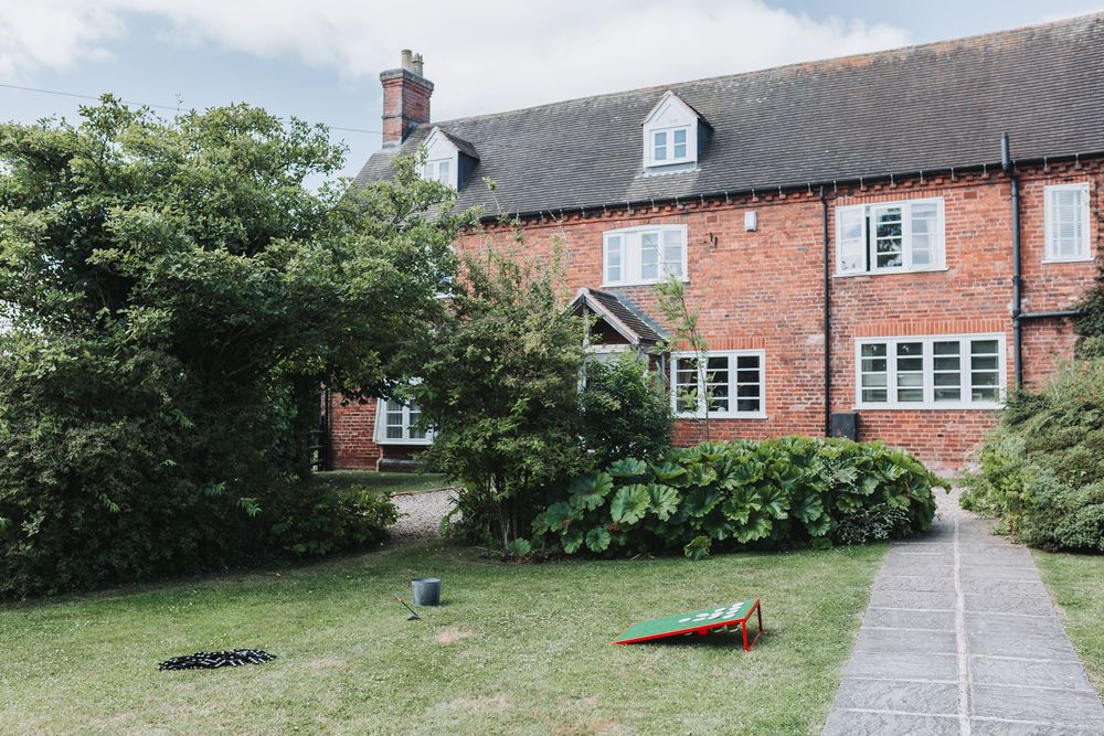 Exterior view of a traditional red brick country house with manicured lawn and garden path.