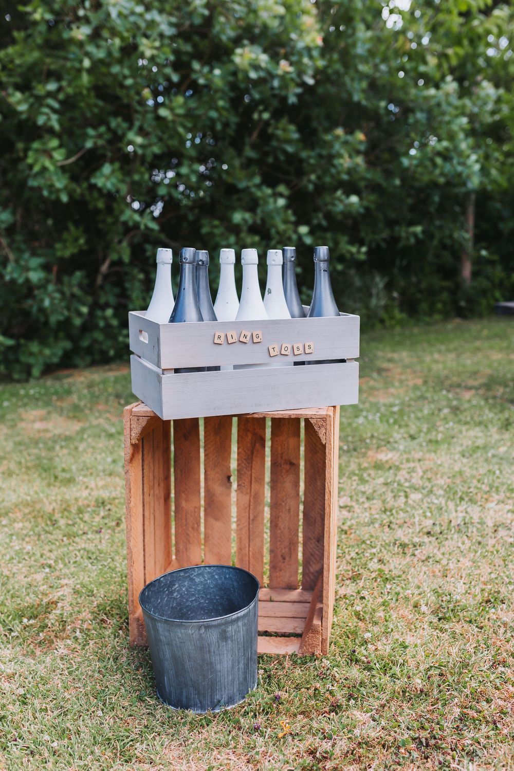 Wooden crate drink station with metal buckets set up on grassy lawn for outdoor event.