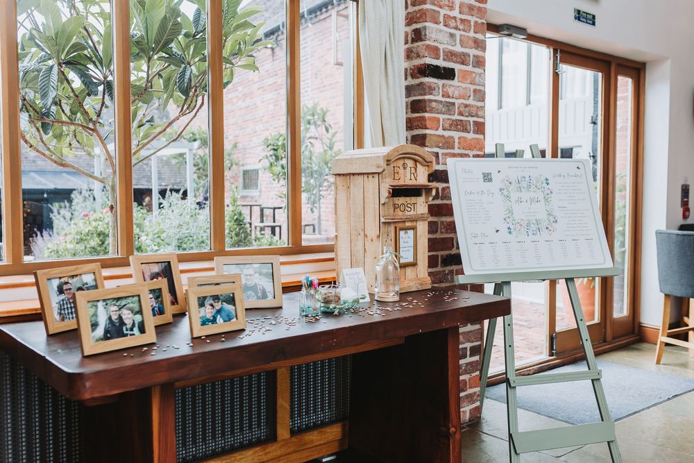 Bright interior room with exposed brick walls, large windows, and wooden beams in rustic venue space.