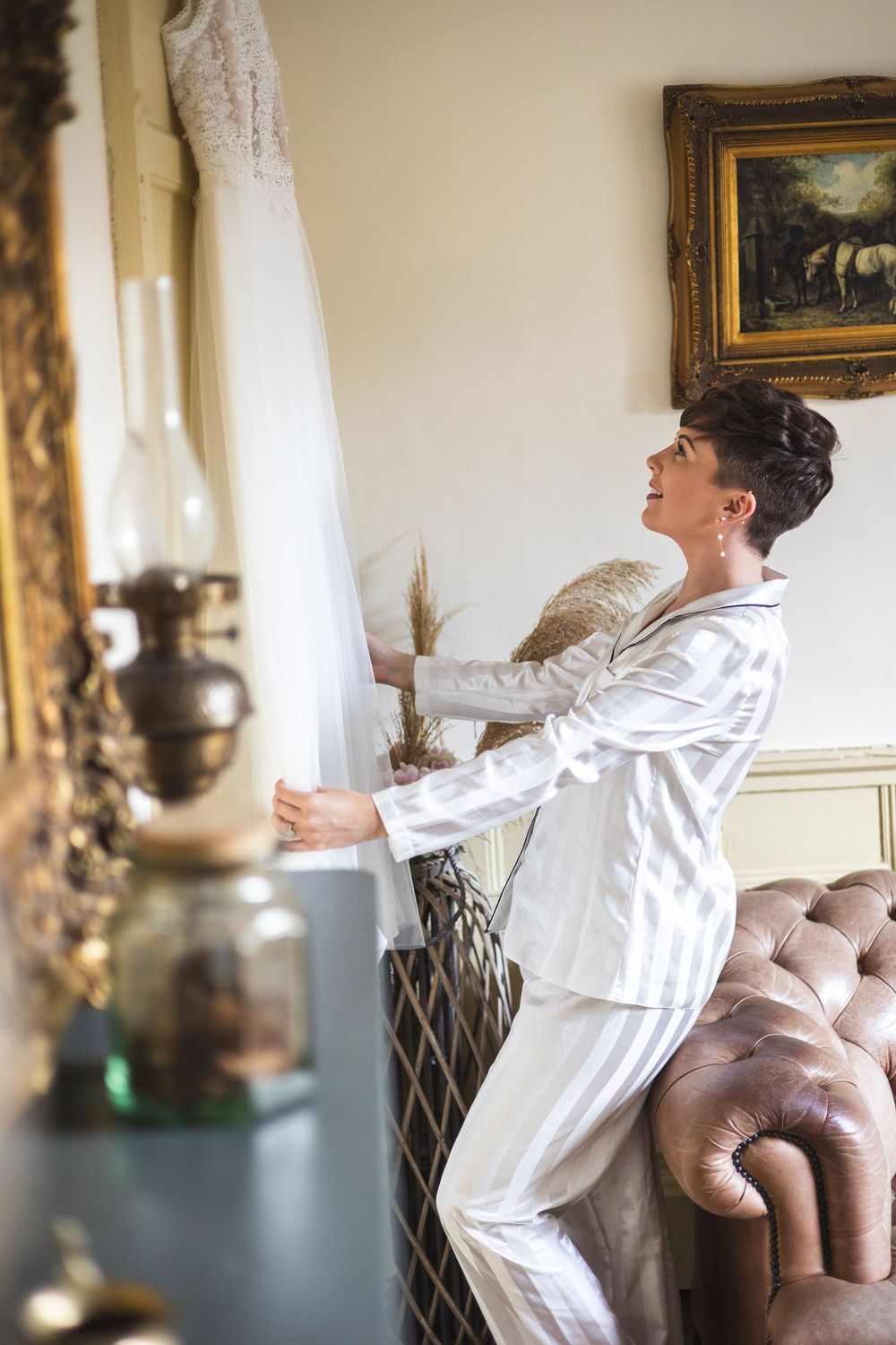 Person in white robe stretching joyfully in an elegant room with vintage decor and natural light.