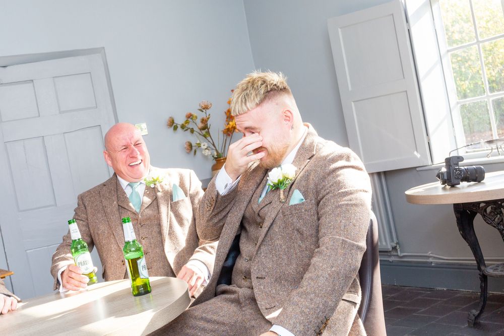Group of people laughing and enjoying drinks together in a bright modern kitchen setting.