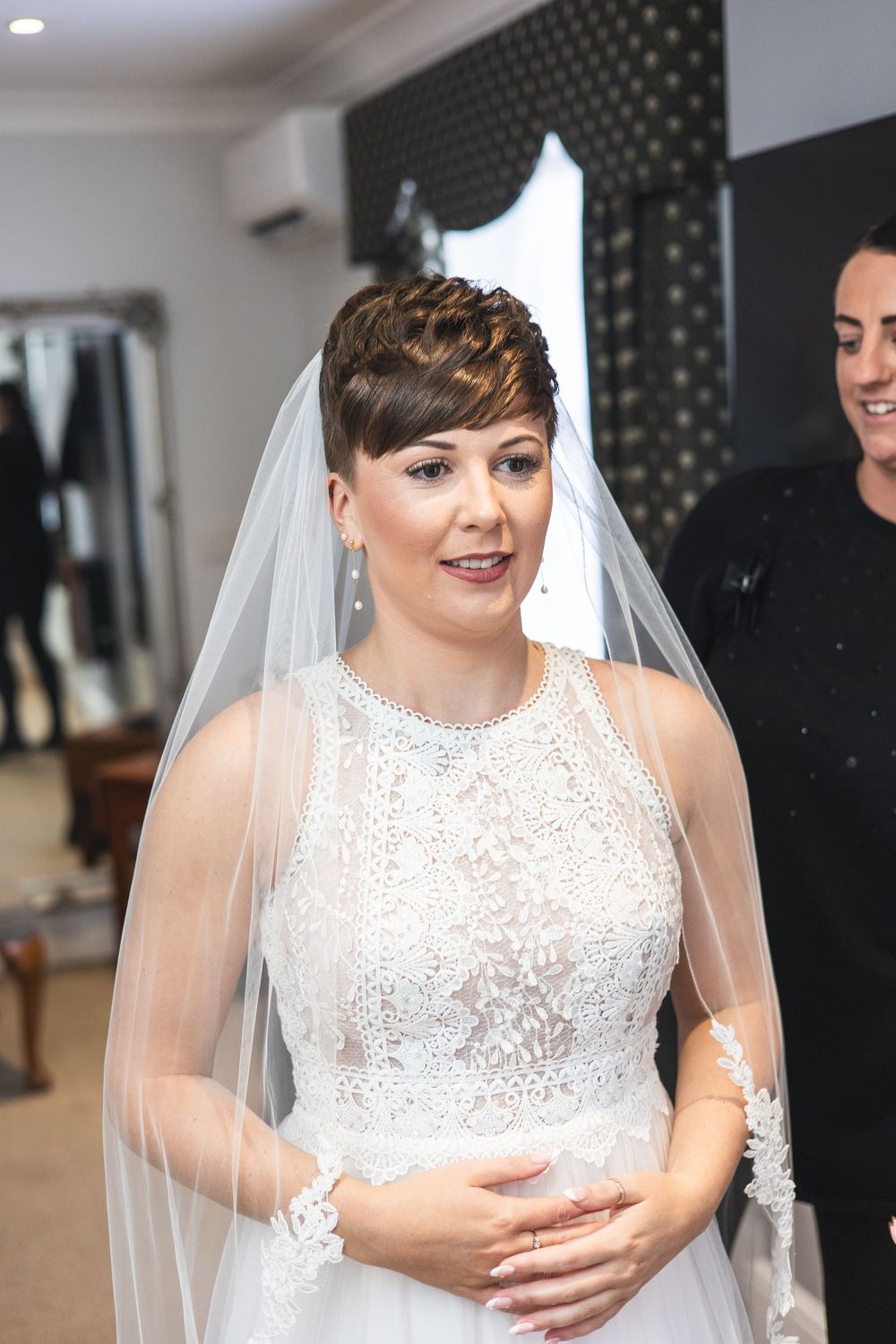 Bride wearing a sparkly white sleeveless wedding dress with veil in an indoor setting.
