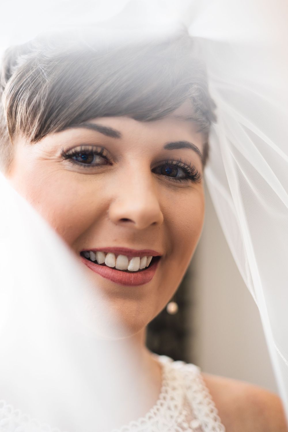Close-up bridal portrait showing delicate lace veil and natural makeup.