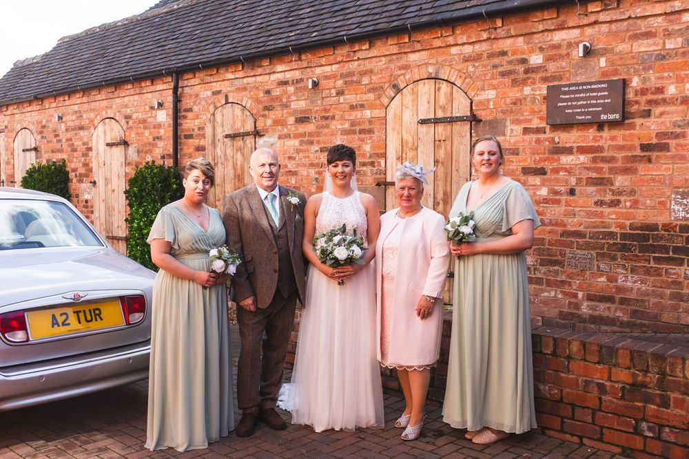 Wedding party poses in front of rustic brick building on special day.