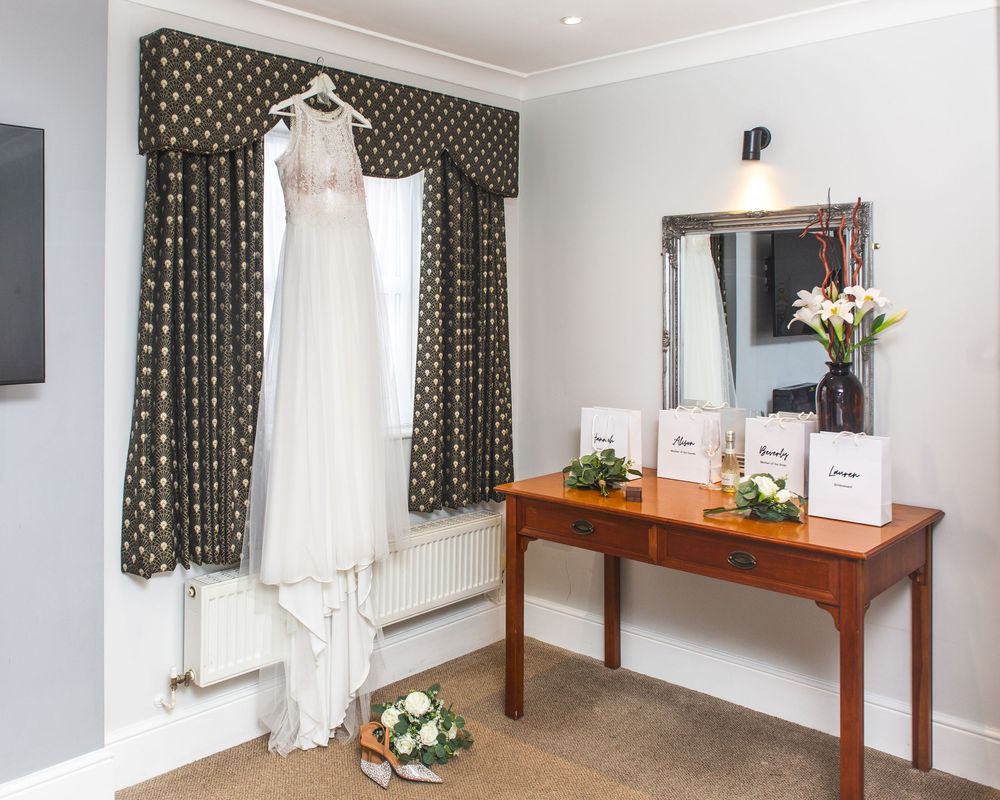 A bright hotel room interior with polka dot curtains, wooden furniture, and white walls shows a clean and modern design.