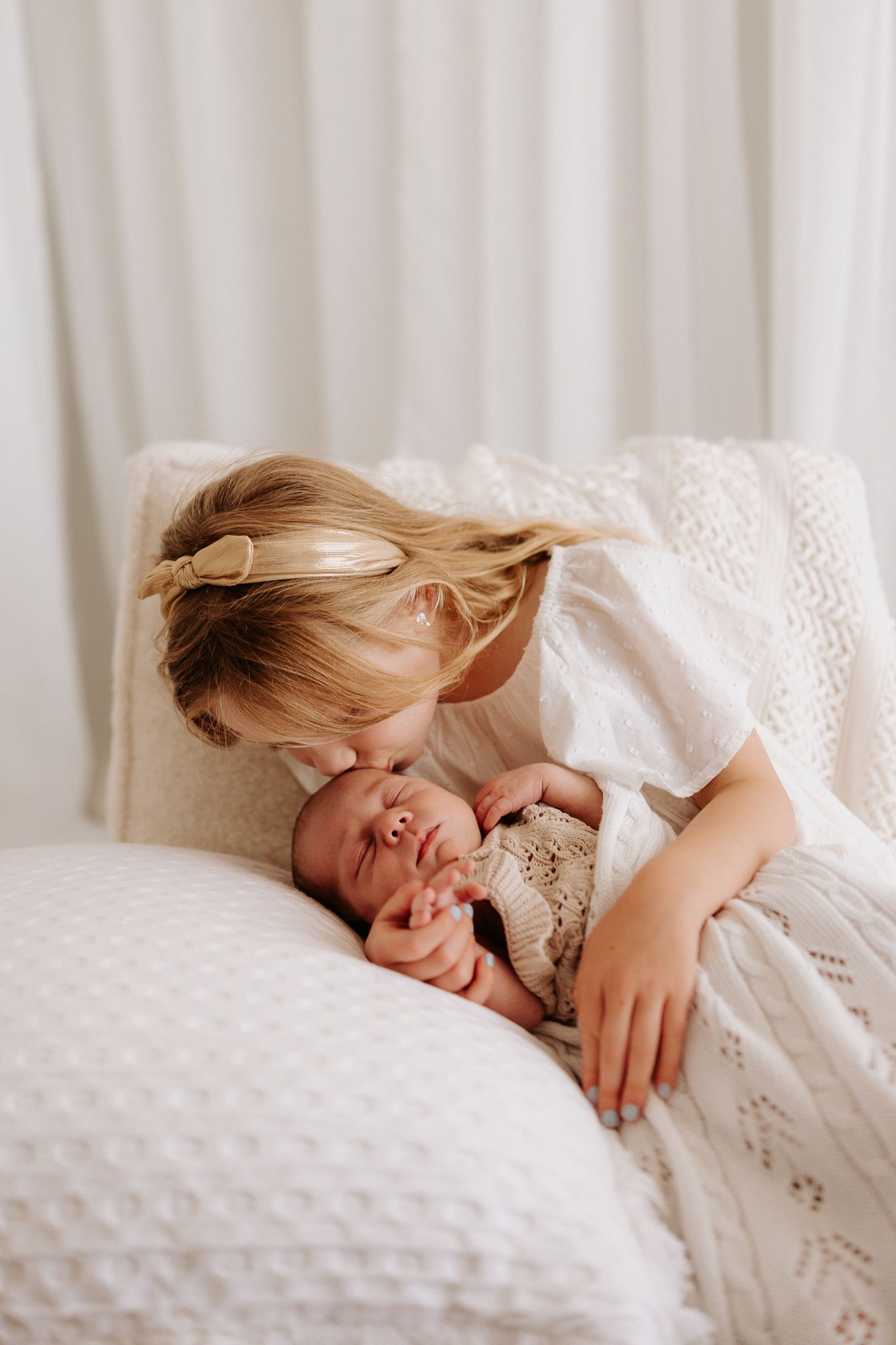A collage of four close-up shots showing a sleeping newborn baby in white blankets with peaceful expressions.